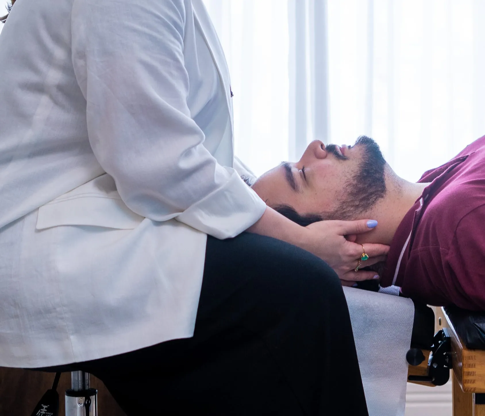 Dra. Vitória fazendo um ajuste cervical em um paciente deitado